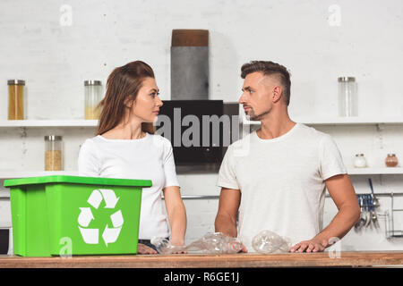 Hot woman with green recycle fort et bouteilles vides en plastique à table de cuisine Banque D'Images
