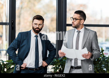 Serious businessmen standing ensemble et discuter de projet au bureau Banque D'Images
