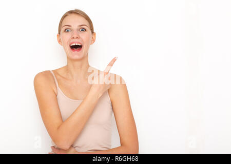 Portrait of happy surpris jeune femme modèle indique à l'endroit montre du doigt pour votre publicité ou texte promotionnel. Banque D'Images