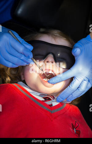 Jeune fille 4 an / enfant de quatre ans portant des lunettes de soleil de protection lors de l'enregistrement jusqu'à la chirurgie du NHS / cabinet dentaire. Royaume-uni (104) Banque D'Images
