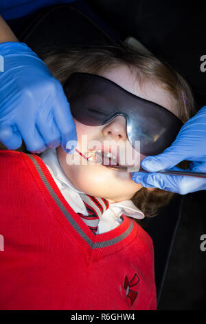 Jeune fille 4 an / enfant de quatre ans portant des lunettes de soleil de protection lors de l'enregistrement jusqu'à la chirurgie du NHS / cabinet dentaire. Royaume-uni (104) Banque D'Images