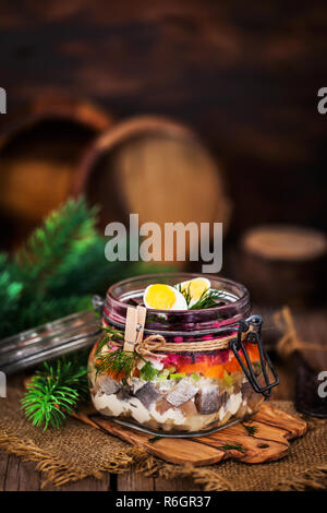 Betroot en couches traditionnel russe et salade de harengs (sous un manteau de fourrure) dans un bocal en verre en bois rustique, background, selective focus Banque D'Images