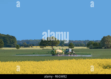 Agriculteur dans le tracteur l'épandage d'herbicides / insecticides / pesticides sur terrain avec pulvérisateur traîné au printemps Banque D'Images