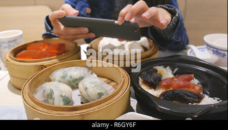 Woman taking photo with cellphone sur dim sum chinois Banque D'Images