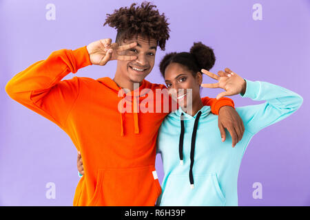 Photo de teenage african american woman et montrant des signes de paix sur fond violet isolés Banque D'Images