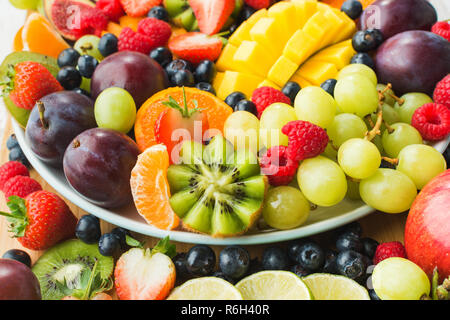 Un assortiment de fruits et de baies, fraises, bleuets plateau orange Mangue, Pommes, raisins, kiwis background, selective focus Banque D'Images