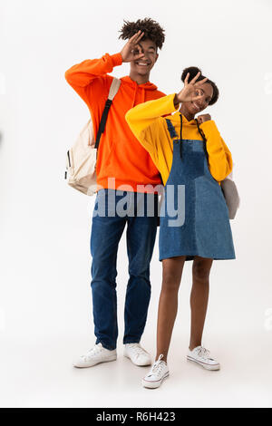 Photo pleine longueur de teen african american couple dans des vêtements colorés smiling while showing ok sign isolé sur fond blanc Banque D'Images