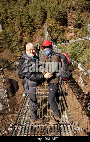 Le Népal, Jorsale (Thumbug), premier guide Sherpa et trekker crossing metal pont suspendu au-dessus de Dudh Sculpture khosi Banque D'Images