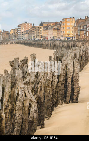 Poteaux en bois à Saint Malo plage avec les édifices de la ville au loin (Bretagne, France) Banque D'Images