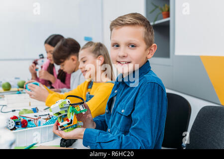 Boy showing robot robotique souches colorées au cours leçon Banque D'Images