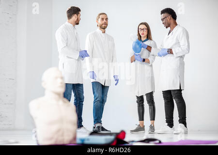 Groupe de jeunes membres du comité permanent et de parler ensemble pendant la pause de la formation en premiers soins médicaux avec les bébés et sucettes sur le plancher Banque D'Images