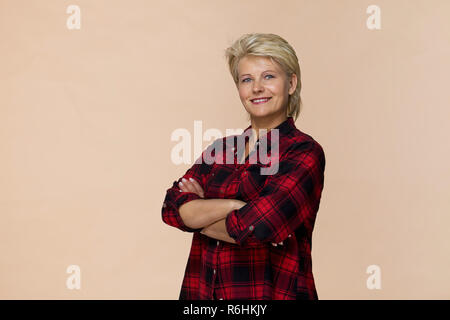 Happy blonde woman smiling portrait chemise à carreaux contre fond brun Banque D'Images