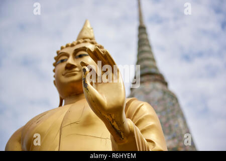 Golden Buddha statue in front of large white dans la Pagode Wat Arun temple à Bangkok, Thaïlande, en mettant l'accent sur la main et out-of-focus l'arrière-plan. Banque D'Images