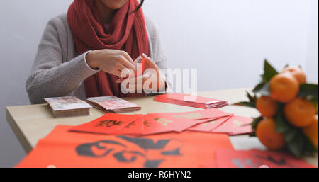 Woman putting money into paquet rouge pour le nouvel an lunaire Banque D'Images