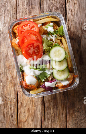 Fast food traditionnel néerlandais kapsalon de frites, poulet, salade fraîche et de la sauce sur la table. Haut Vertical Vue de dessus Banque D'Images