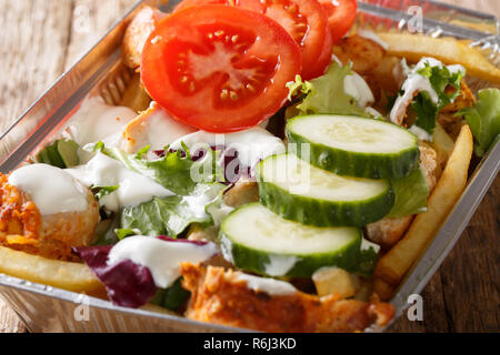 Fast food traditionnel néerlandais kapsalon de frites, poulet, salade fraîche et de la sauce sur la table. L'horizontale Banque D'Images