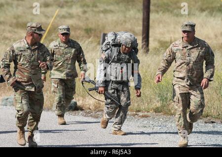 Le Sgt. Jacob T. Penaflor, centre, de l'Army National Guard, reçoit les encouragements de Sgt. 1re classe Kevin Dirige, commande le Sgt. Le Major Ken Cruz et le sergent. Dino Cruz comme Penaflor arrive à la fin de l'épuisant 12-mile ruck sack mars mai 18 au cours de la Garde nationale 2017 Région Bureau VII CONCOURS Meilleur guerrier 17 mai à San Luis Obispo, Californie. Les concurrents avaient à transporter un 35 livres de matériel tout au long de la région vallonnée, isolée bien sûr. Banque D'Images