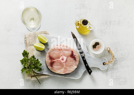 Steak d'espadon cru sur une planche à découper en marbre avec de l'huile d'olive et épices Banque D'Images