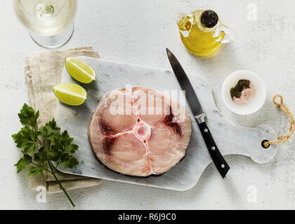 Steak d'espadon cru sur une planche à découper en marbre avec de l'huile d'olive et épices Banque D'Images