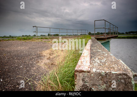 Vieux et délabrés vintage rempart le long du bord de la rivière dans un landaschap des Pays-Bas. Jetée d'amarrage en béton abandonnés en l'état. Banque D'Images