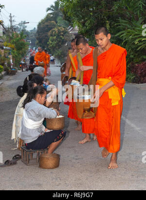 Moines en robe safran prendre l'aumône à l'aube de la population locale dans la ville de Luang Prabang, Laos, Asie du sud-est Banque D'Images