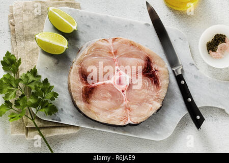 Steak d'espadon cru sur une planche à découper en marbre avec de l'huile d'olive et épices Banque D'Images