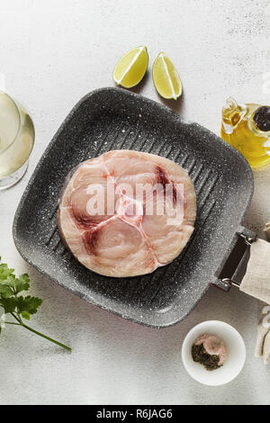 Steak d'espadon cru sur la poêle avec l'huile d'olive et les épices, de verre de vin blanc Banque D'Images