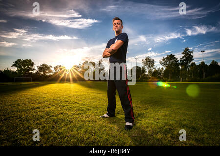 Coucher de soleil avec des rayons de soleil sur un terrain de sport vert. Banque D'Images