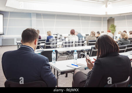 L'homme et de la femme d'affaires avec des personnes et à l'écoute sur la conférence ou sur la formation dans le hall Banque D'Images
