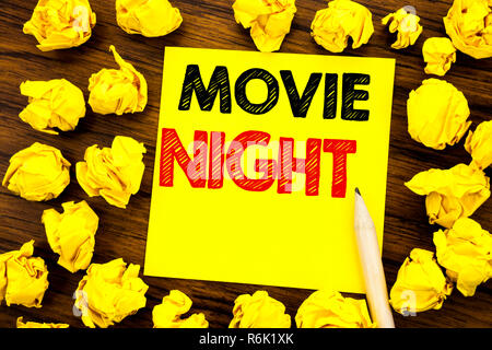 L'écriture de texte montrant Movie Night. Concept d'affaires pour Wathing Movies écrit le post-it, le papier de fond en bois plié avec du papier jaune sens penser Banque D'Images