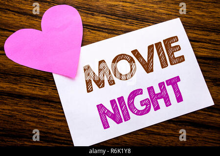 Par contre l'écriture de texte conceptuel montrant Movie Night. Concept pour Wathing Movies écrit le post-it papier, bois en arrière-plan. Coeur rose avec amour sens adoration. Banque D'Images