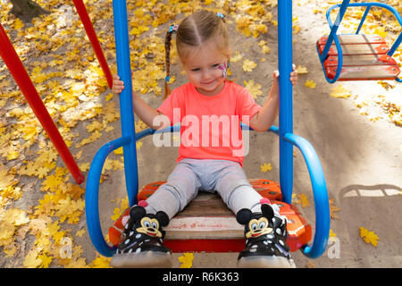 Petite fille se balançant sur la balançoire dans le parc Banque D'Images