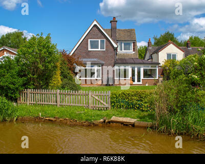 Maison au bord du canal sur le canal de Trent et Mersey dans le West Midlands en Angleterre. Vue depuis le bateau. Banque D'Images