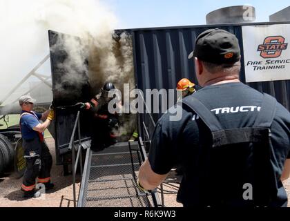 Les députés de la 97e Escadron de génie civile Pompiers quitter le simulateur d'embrasement du feu, le 17 mai 2017, à la base de la Force aérienne Altus, Arkansas. Des instructeurs de l'Université d'Oklahoma a aidé à la formation des pompiers de la 97e SCÉ sur flashovers. Flashovers se produisent lorsque la chaleur d'un incendie et une inondation soudaine d'oxygène provoquer une petite explosion dans la salle. Banque D'Images