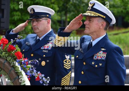 Master Chief Petty Officer de la Garde côtière et de la Garde côtière Steven Cantrell Commandant Adm. Paul Zukunft saluer une couronne placée en face d'une photo de la garde-côte de Tampa et de l'équipage au cours d'une célébration de la Journée du souvenir à la Douglas A. Munro du bâtiment du siège de la Garde côtière canadienne à Washington, D.C., le 26 mai 2017. La Faucheuse Tampa a été torpillé après avoir escorté un convoi de Galles en 1918, entraînant la perte de toutes les 131 personnes à bord. La Garde côtière américaine Banque D'Images