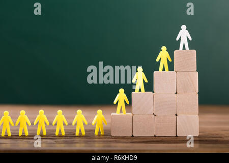 La figure blanche menant des personnages humains sur haut de blocs de bois Banque D'Images