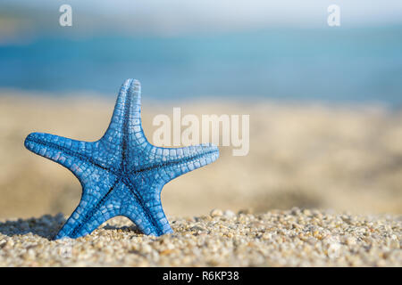 L'étoile bleue épinglée sur le sable à la plage. Bleu de la mer sur l'arrière-plan. Banque D'Images