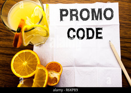 Légende de texte conceptuel montrant le code promo. Concept pour la promotion des affaires en ligne écrit sur le papier de soie sur le fond en bois avec un stylo et de jus de fruits orange sain dans le restaurant Banque D'Images