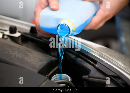 Homme mains tiennent une bouteille d'antigel en bleu Banque D'Images