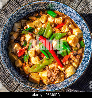 Le Mapo Tofu - le tofu, le porc et les légumes dans une sauce sauce chinoise, frais généraux indiqués dans un bol sur une surface en bois Banque D'Images