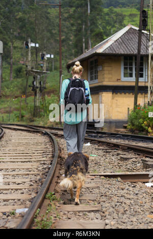 Backpacker femelle marche sur voie ferrée, suivi par son chien. Banque D'Images