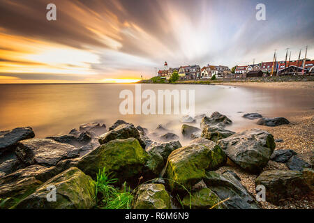 Phare et village de l'ancienne île d'Urk au bord du lac IJsselmeer, longue exposition avec de l'eau lisse et dynamique coucher du soleil dans le Netherland Banque D'Images