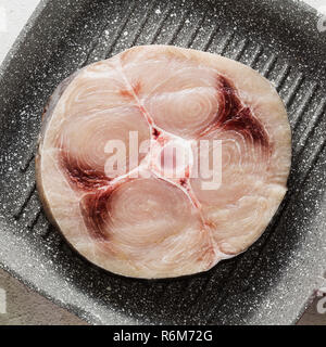 Steak d'espadon cru sur la poêle avec l'huile d'olive et les épices, de verre de vin blanc Banque D'Images