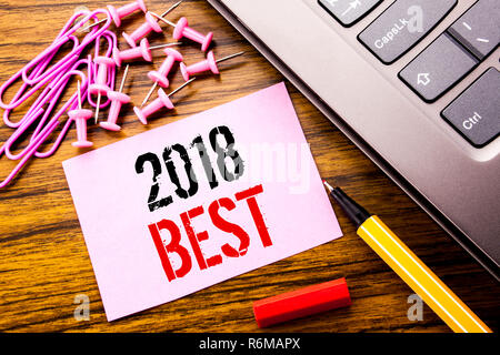 Texte manuscrit montrant 2018 meilleure. Concept d'affaires Choix de revue écrite sur papier rose post-it sur le fond de bois à côté du clavier. Avec stylo rouge. Banque D'Images