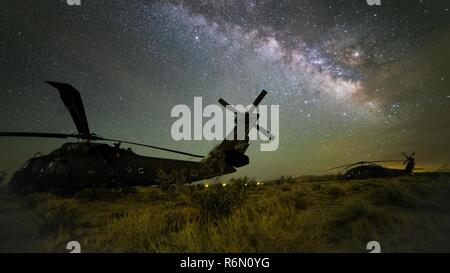 Un hélicoptère Blackhawk UH-60 se situe sous voie lactée dans le désert de Mojave, le 30 mai 2017, au Centre National d'entraînement, à Fort Irwin, en Californie. L'exposition de 25 secondes a été prise lorsque la lune se couchait, illuminant les nuages d'un côté de l'horizon. Plus de détails dans la Voie lactée a été mis en évidence par l'empilement de 10 images ensemble. Des soldats de la Compagnie C, 1er Bataillon, 106e Régiment d'aviation, sont à l'entraînement au combat des NTC à renforcer leurs compétences individuelles et la préparation au combat. créé à l'aide de techniques d'exposition longue et l'empilage) Banque D'Images