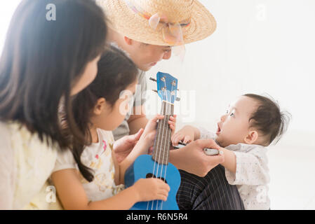 Asian family playing ukulele et de l'harmonica à la maison Banque D'Images