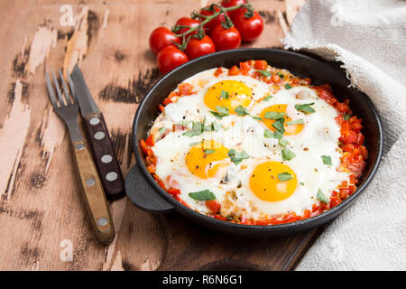 Shakshuka sains et savoureux dans une poêle. Oeufs au plat avec tomates, poivrons, légumes et fines herbes. Plat traditionnel du Moyen-Orient. Banque D'Images