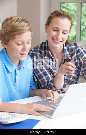 Accueil tuteur femelle aider Boy avec des études à l'aide d'un ordinateur portable Banque D'Images