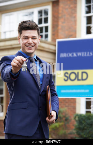 Homme debout à l'extérieur de la propriété de l'agent immobilier résidentiel Holding Keys Banque D'Images