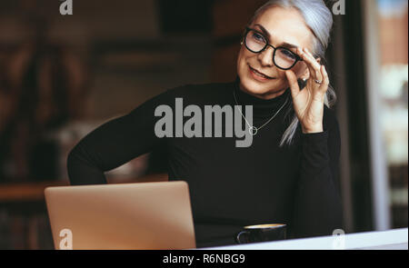 Magnifique Portrait de senior businesswoman sitting at cafe avec coffre à l'écart et la pensée. Femme mature au coffee shop. Banque D'Images